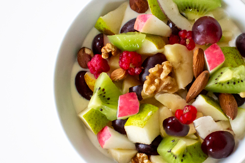 Oktobers frugtbowle med yoghurt, nødder, hindbær, blåbær, kiwi, pære og druer.